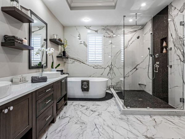 Luxury bathroom remodel in Philadelphia featuring full marble walls and floors, freestanding soaking tub, glass walk-in shower, and dark wood double vanity