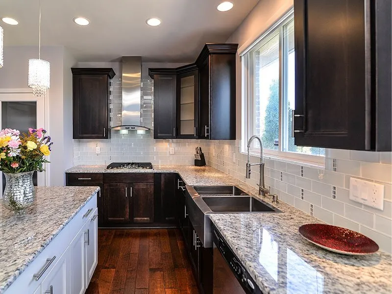 Beautifully completed kitchen cabinet refacing in Philadelphia featuring dark wood cabinets, granite countertops, white subway tile backsplash, and hardwood flooring.