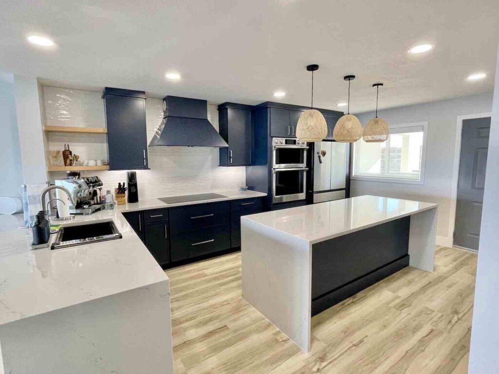 Modern kitchen remodel in Philadelphia featuring navy blue shaker cabinets, white quartz countertops, center island, and rattan pendant lights